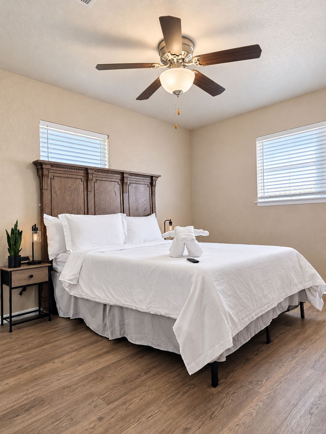 A bedroom with a bed, a nightstand, a ceiling fan, and a window.