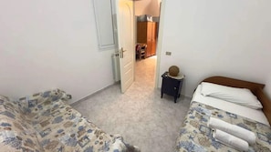 Ein Schlafzimmer mit zwei Betten, einem Nachttisch und einer Tür zu einem Badezimmer.