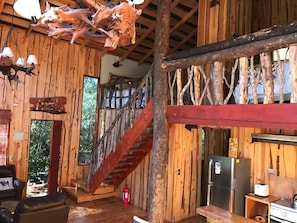 A rustic cabin interior with a wooden staircase, a dining area, and a kitchen. - New Listing (Quetroleufu)