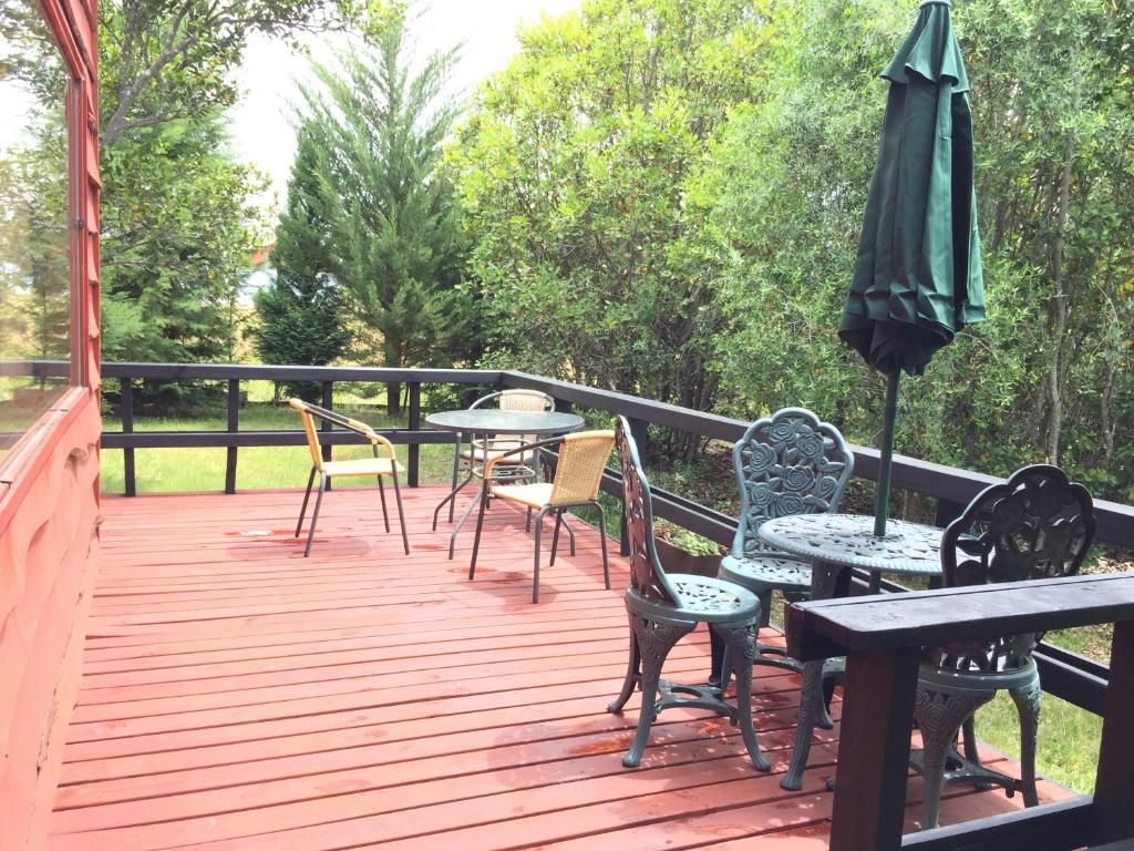 A covered outdoor deck with wooden flooring, metal tables, and chairs.