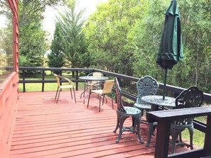 A covered outdoor deck with wooden flooring, metal tables, and chairs. - New Listing (Quetroleufu)