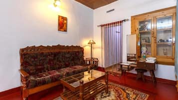 A room with a sofa, a table, a lamp, a window with curtains, and a cabinet with glass doors.