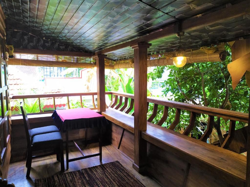 An outdoor seating area with wooden benches and tables, surrounded by a wooden railing, overlooking a lush garden.