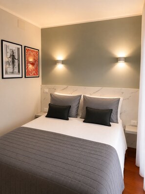 A hotel room with a bed, two wall-mounted lights, a marble headboard, and two framed pictures. - AE Nova Studio – Panoramic Views of Caserta (Caserta)