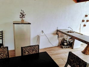 A compact kitchen with a refrigerator, sink, and tiled backsplash. - Miniquinta La Chula (Santiago)