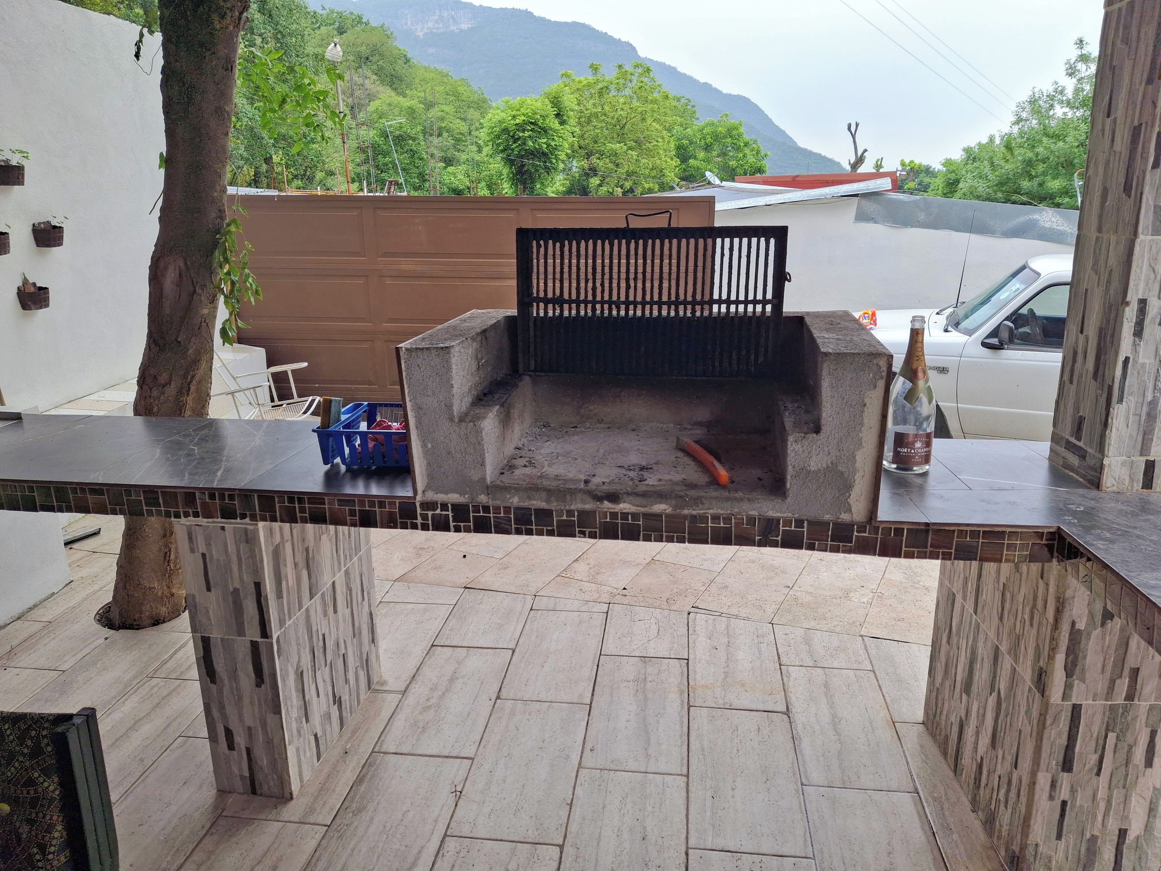 A patio area with a barbecue grill, tiled flooring, and a view of a mountain.