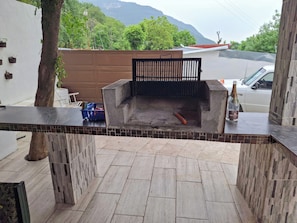 A patio area with a barbecue grill, tiled flooring, and a view of a mountain. - Miniquinta La Chula (Santiago)