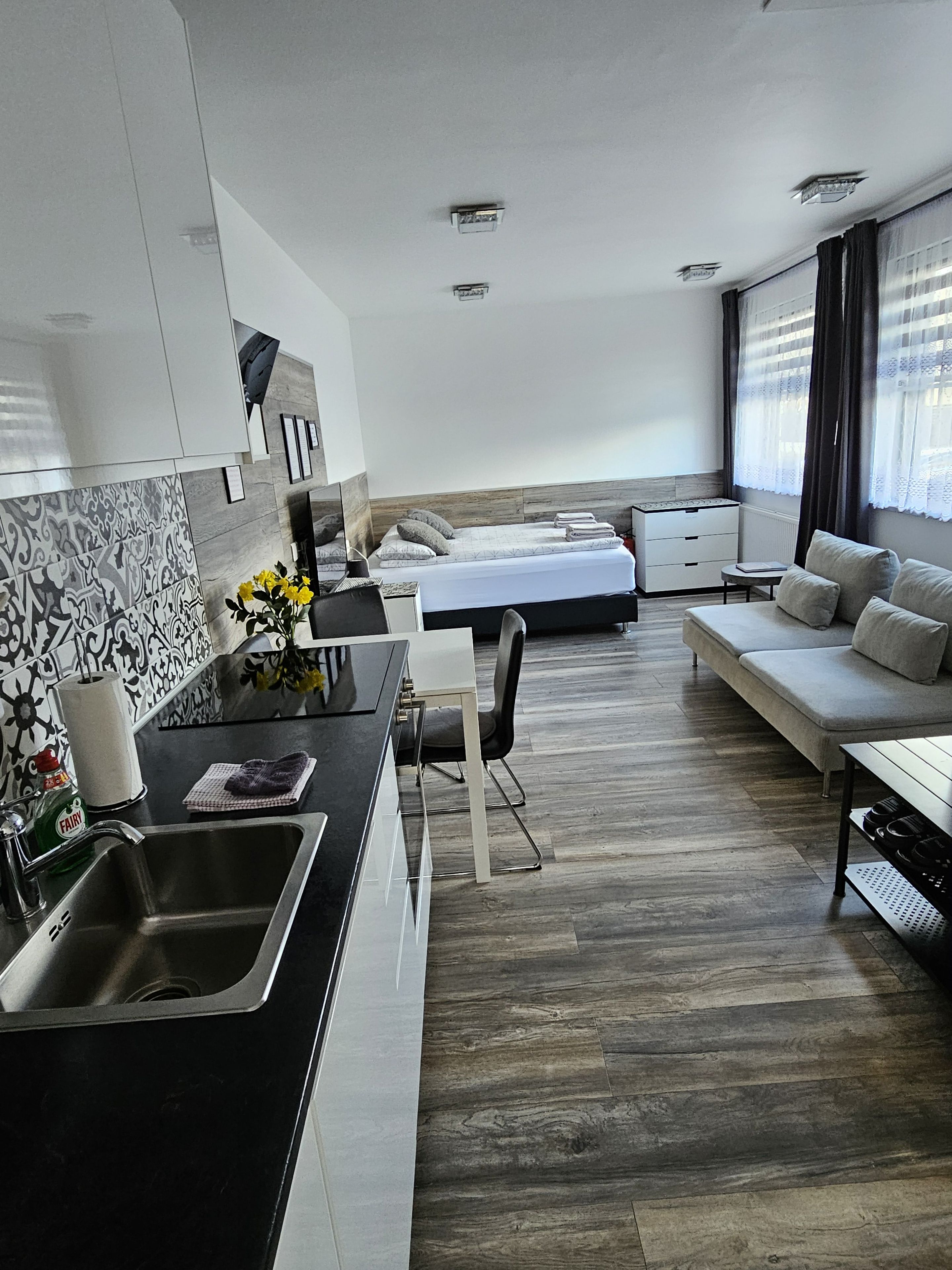Eine moderne Küche mit Spüle, ein Essbereich mit Tisch und Stühlen, ein Sofa und ein Bett im Hintergrund.