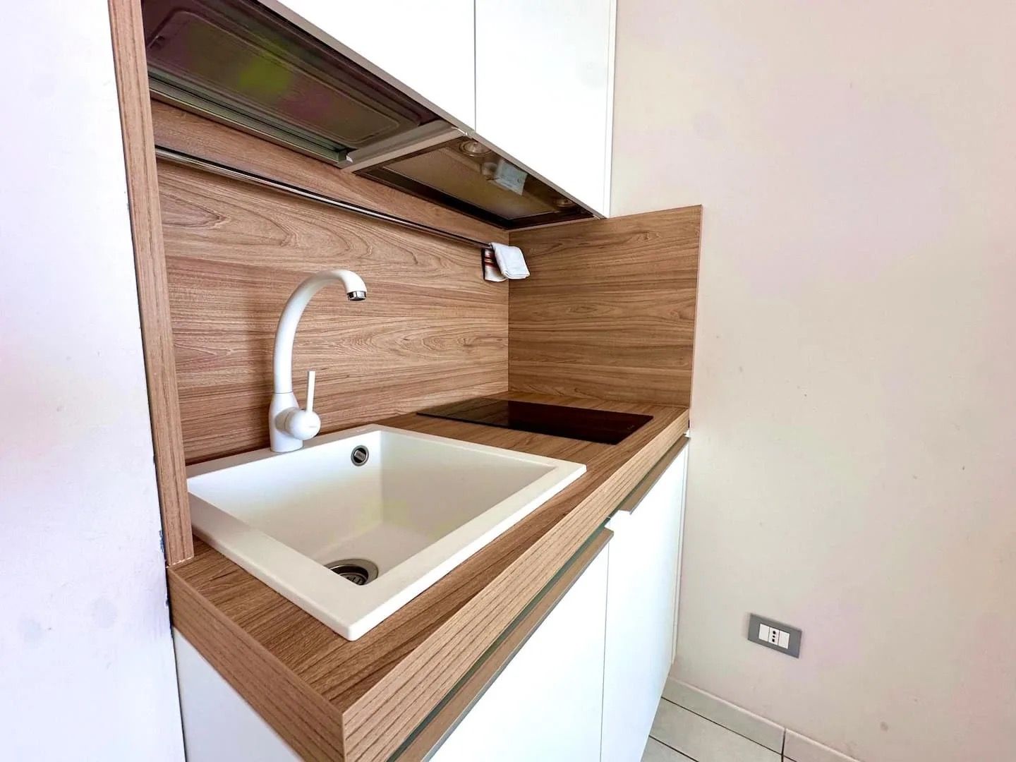 A modern kitchen with a built-in white sink, wooden cabinetry, and a stainless steel faucet.