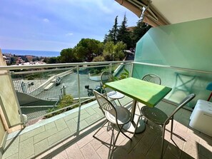 A balcony with a table and chairs, overlooking a parking area and a view of the sea. - New Listing (Sanremo)