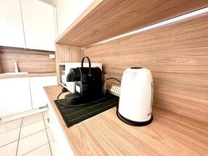 A modern kitchen with a coffee maker, a kettle, and a power strip on a wooden countertop. - New Listing (Sanremo)