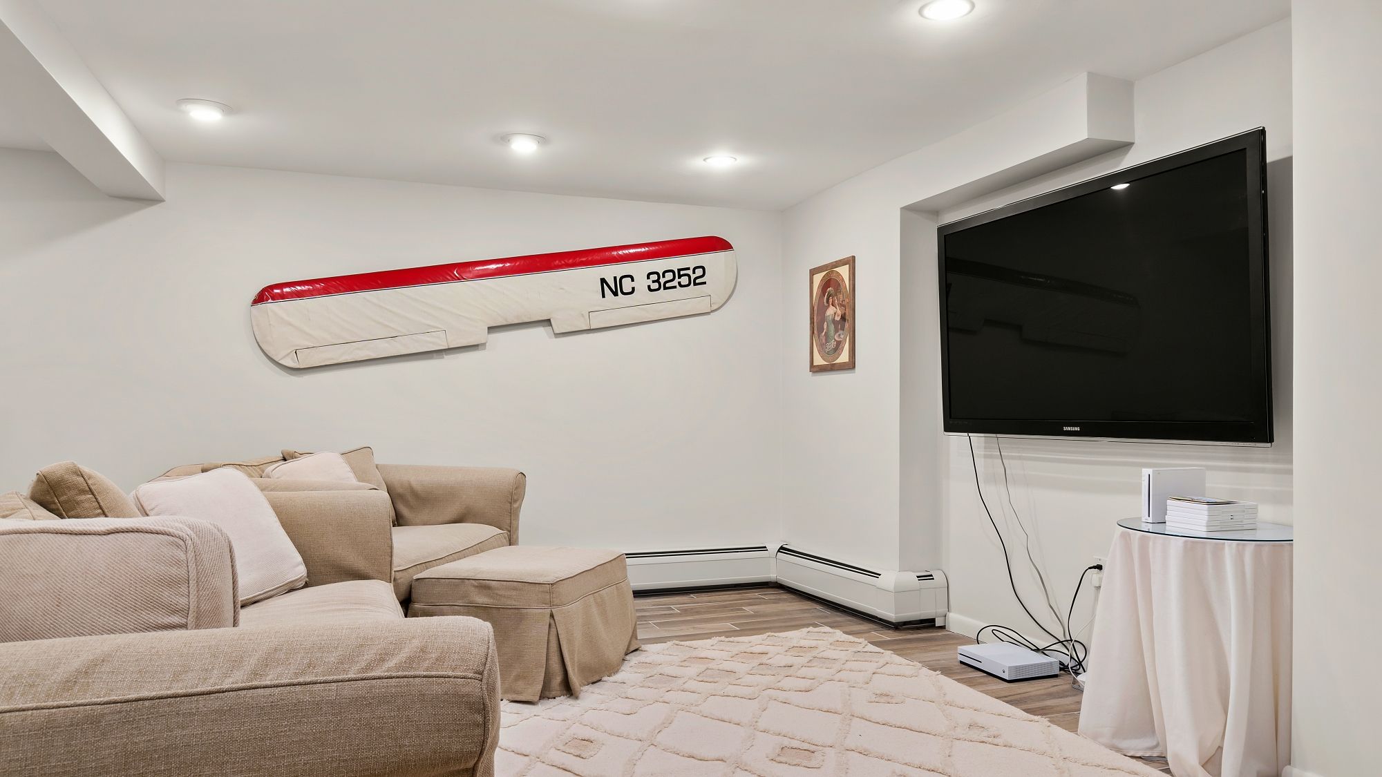 A modern living room with a sectional sofa, a flat-screen TV, and a wall-mounted air conditioning unit.