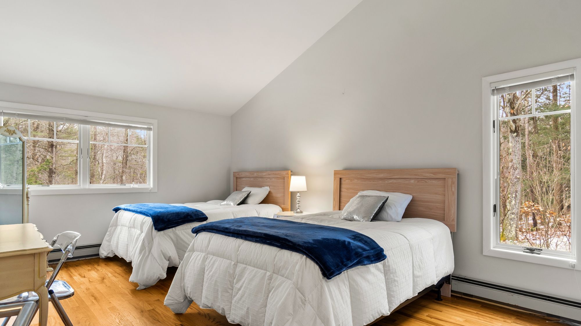 A bedroom with two beds, a desk, and a chair.