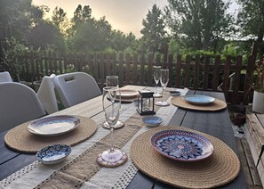 An outdoor dining table set with plates, glasses, and a candle holder.