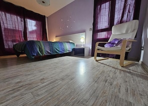 A bedroom with a bed, a chair, a nightstand, and a wall with butterfly decals.