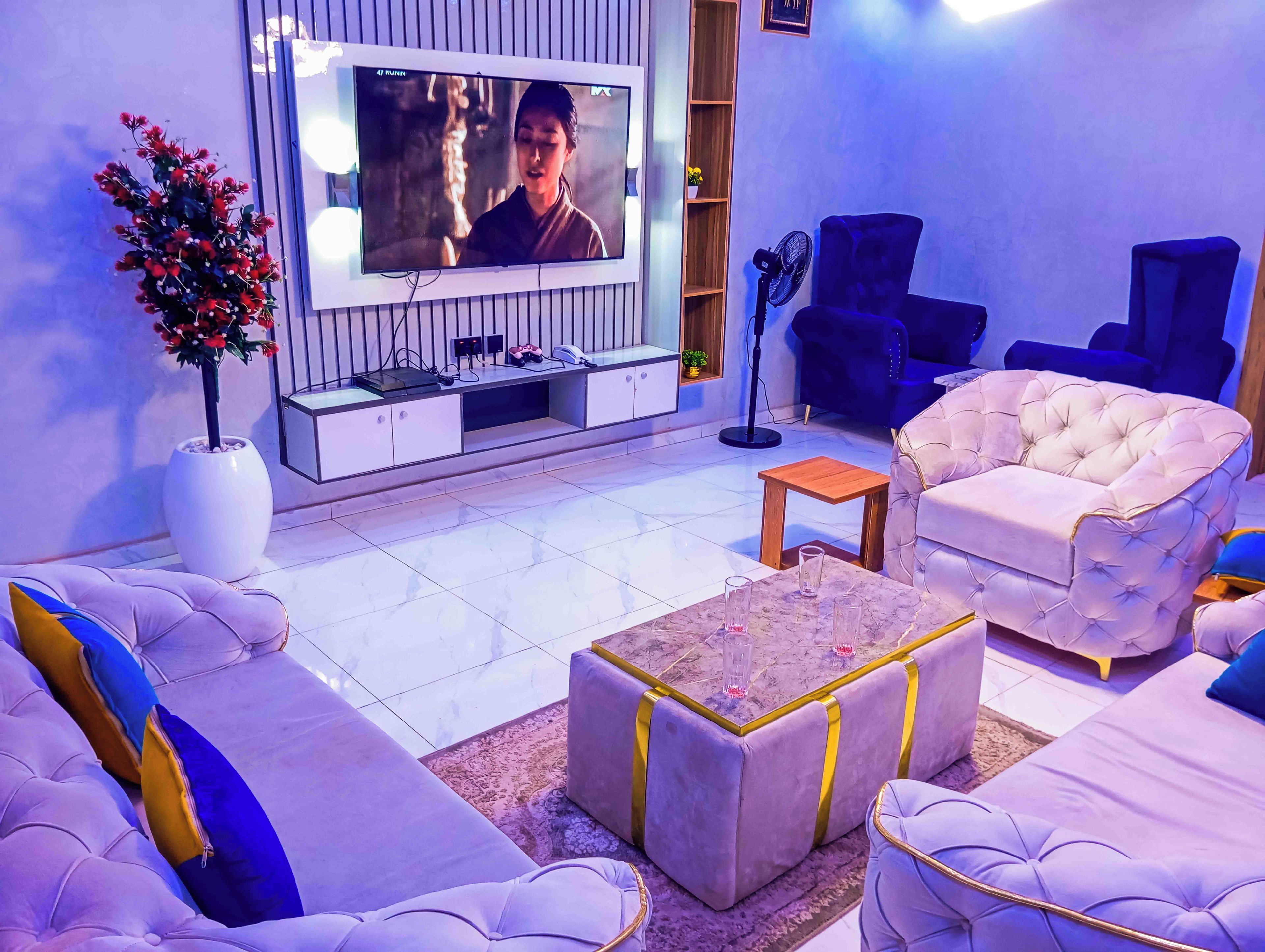Una sala de estar con televisor de pantalla plana, sofás cómodos, una mesa de centro y una planta en maceta.