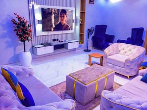Una sala de estar con televisor de pantalla plana, sofás cómodos, una mesa de centro y una planta en maceta.