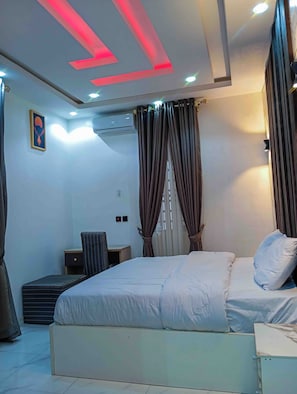 Un dormitorio moderno con cama, cortinas, aire acondicionado y un escritorio.