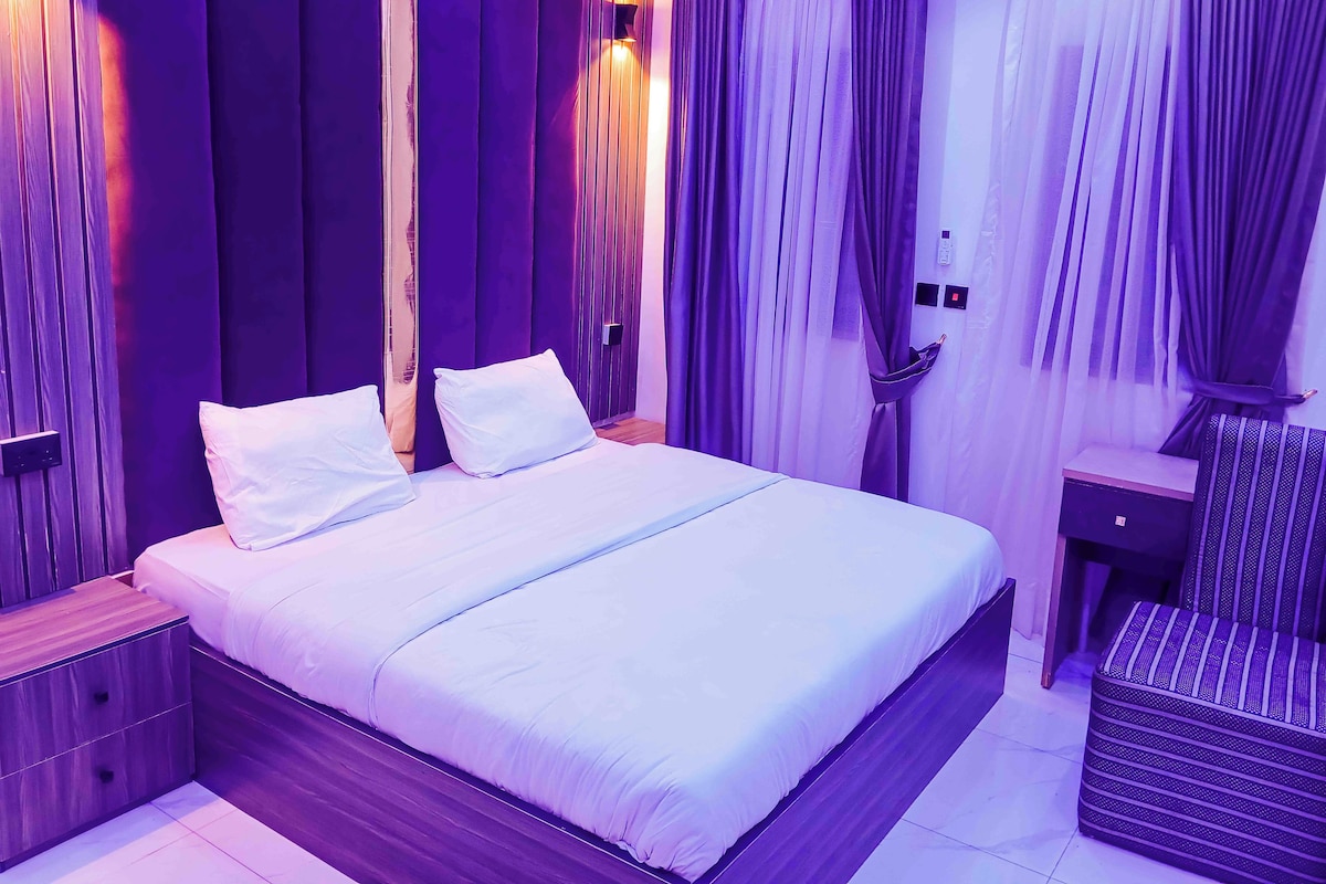 Un dormitorio con cama, dos mesitas de noche y una ventana con cortinas.