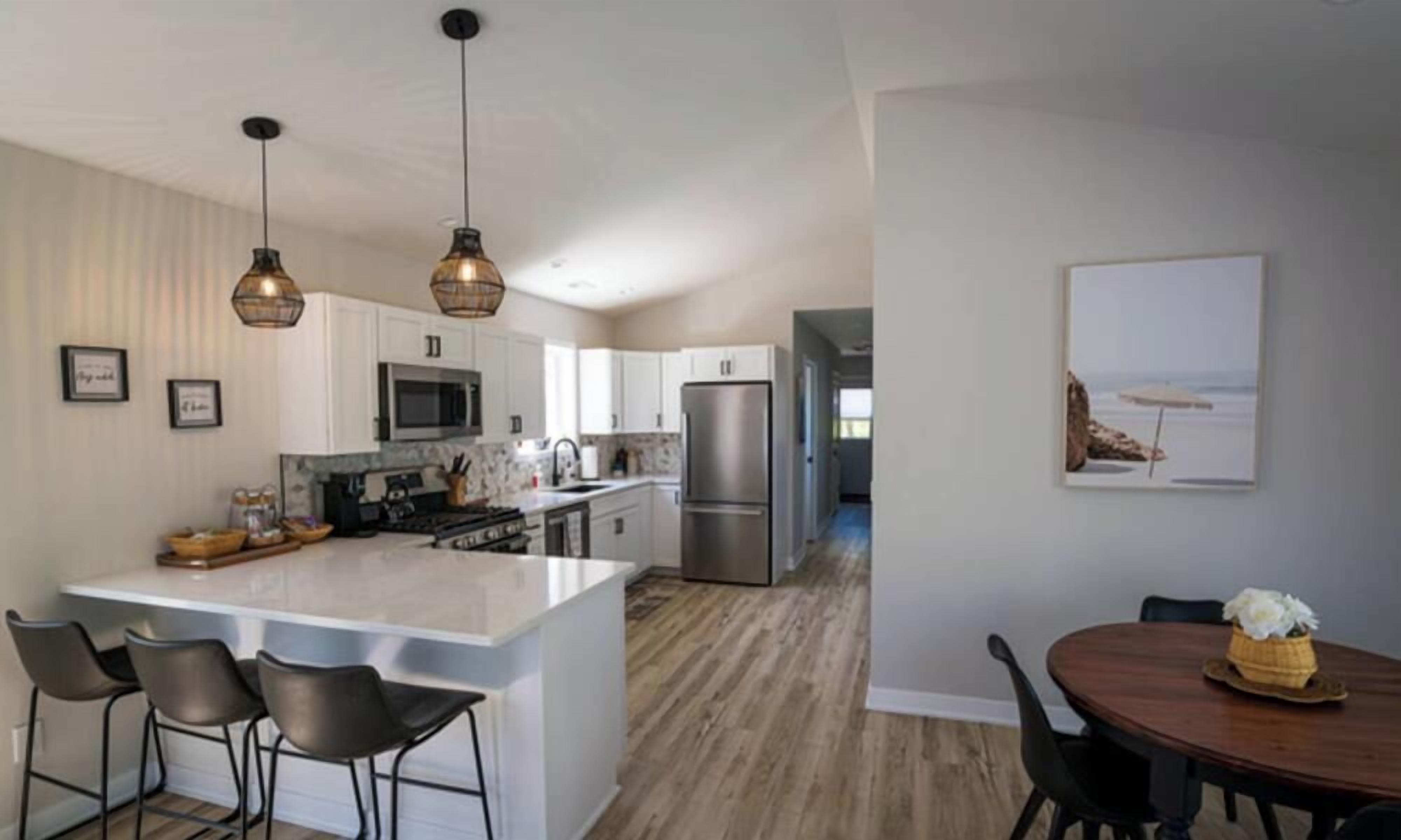 Una cocina moderna con una isla central, taburetes de bar e iluminación colgante.