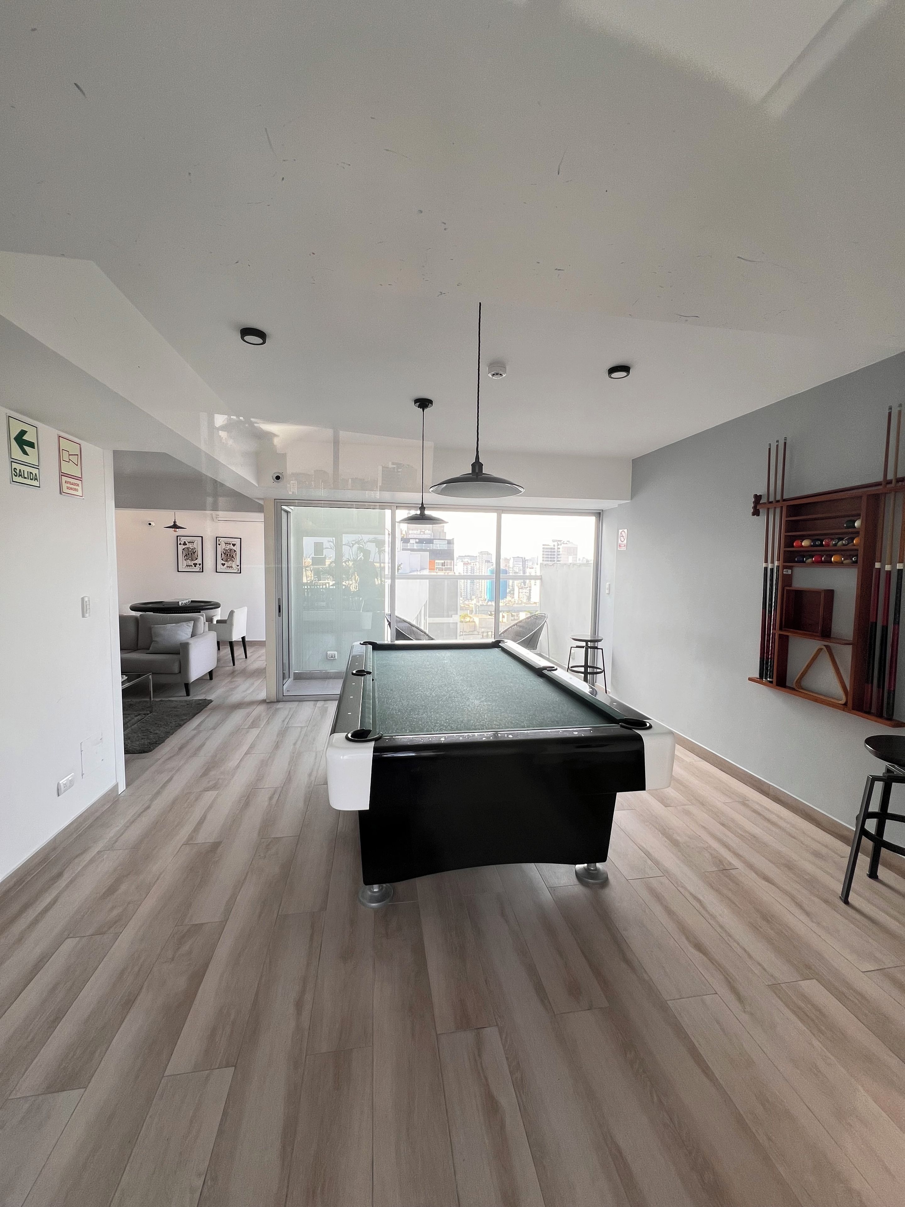 A modern living room with a pool table, a sofa, and a dining area.