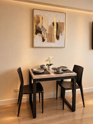 A dining area with a table set for four, a modern abstract painting on the wall, and a potted orchid on the table. - New Listing (Barranco)