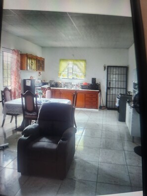 Una sala de estar con sofá, una mesa de comedor con sillas, una zona de cocina con armarios y una ventana con vistas.