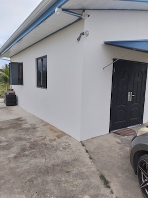 Un edificio blanco con una puerta negra, una ventana y una cámara de seguridad.