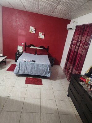 A bedroom with a bed, nightstands, a dresser, and a red curtain.