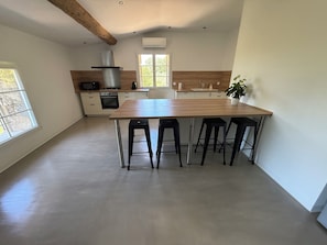 Una cocina moderna con una isla central, electrodomésticos integrados y un amplio ventanal.