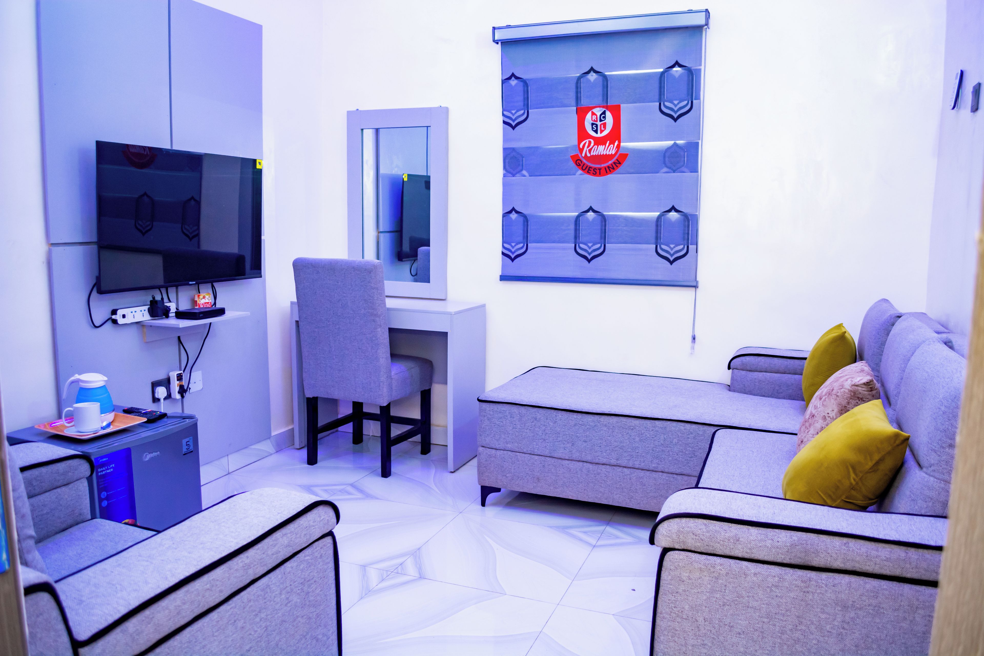 Una sala moderna con una televisión de pantalla plana, un escritorio y un sofá.