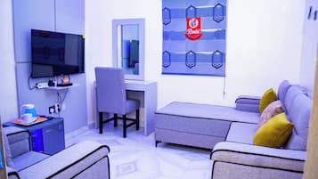 Una sala moderna con una televisión de pantalla plana, un escritorio y un sofá.