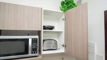 Cozinha com micro-ondas, torradeira e armário com uma planta em cima.
