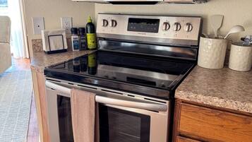 A kitchen with a stainless steel refrigerator, microwave, and oven, wooden cabinets, and a granite countertop.