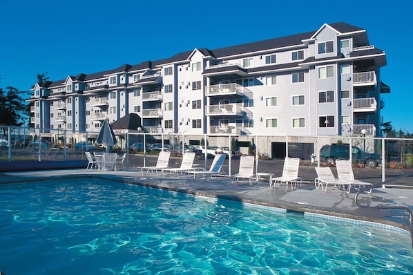 Un hôtel à plusieurs étages doté d’une piscine, de chaises longues et d’un espace abrité.