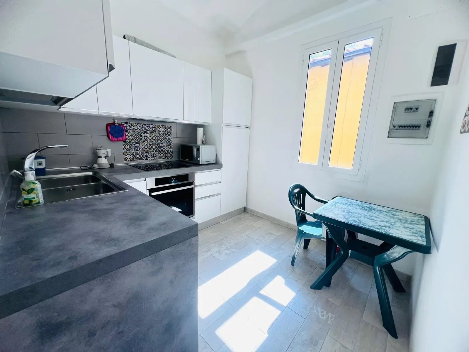 Et moderne køkken med et indbygget komfur, vask og spiseområde med bord og stole.