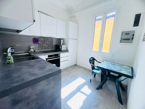 Et moderne køkken med et indbygget komfur, vask og spiseområde med bord og stole.