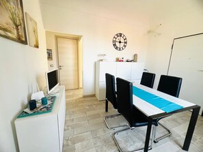 A dining area with a table, chairs, a clock, and a white cabinet. - New Listing (Sanremo)