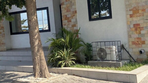 A building with a stone facade, a tree, and a fan on the ground.