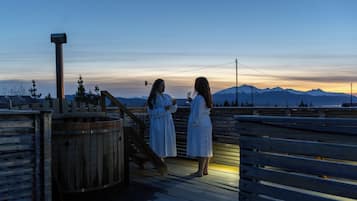 Dos personas en una cubierta de madera con vistas a un paisaje montañoso.