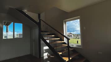 Un interior moderno con una escalera de madera, un ventanal y vistas al exterior.