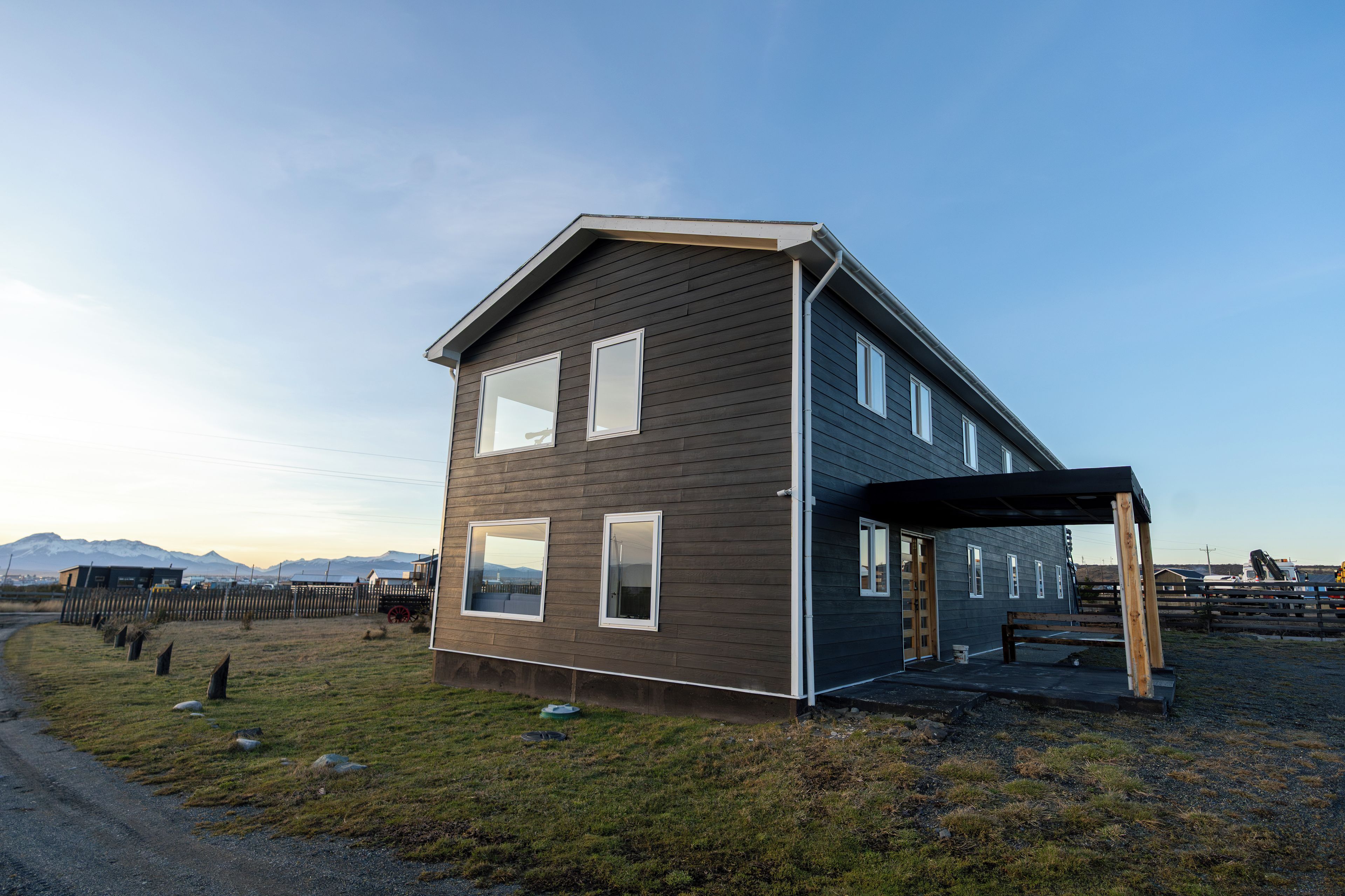 A modern two-story house with a sloped roof, large windows, and a covered porch area.