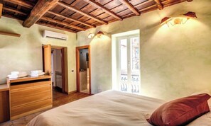 Un dormitorio con techo de madera, una cama con almohada roja, un aparador de madera y una ventana con vistas.