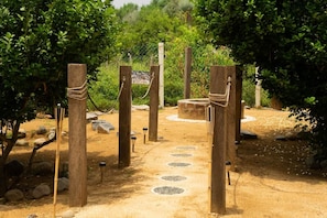 A pathway leading to a circular stone structure surrounded by wooden posts with ropes.