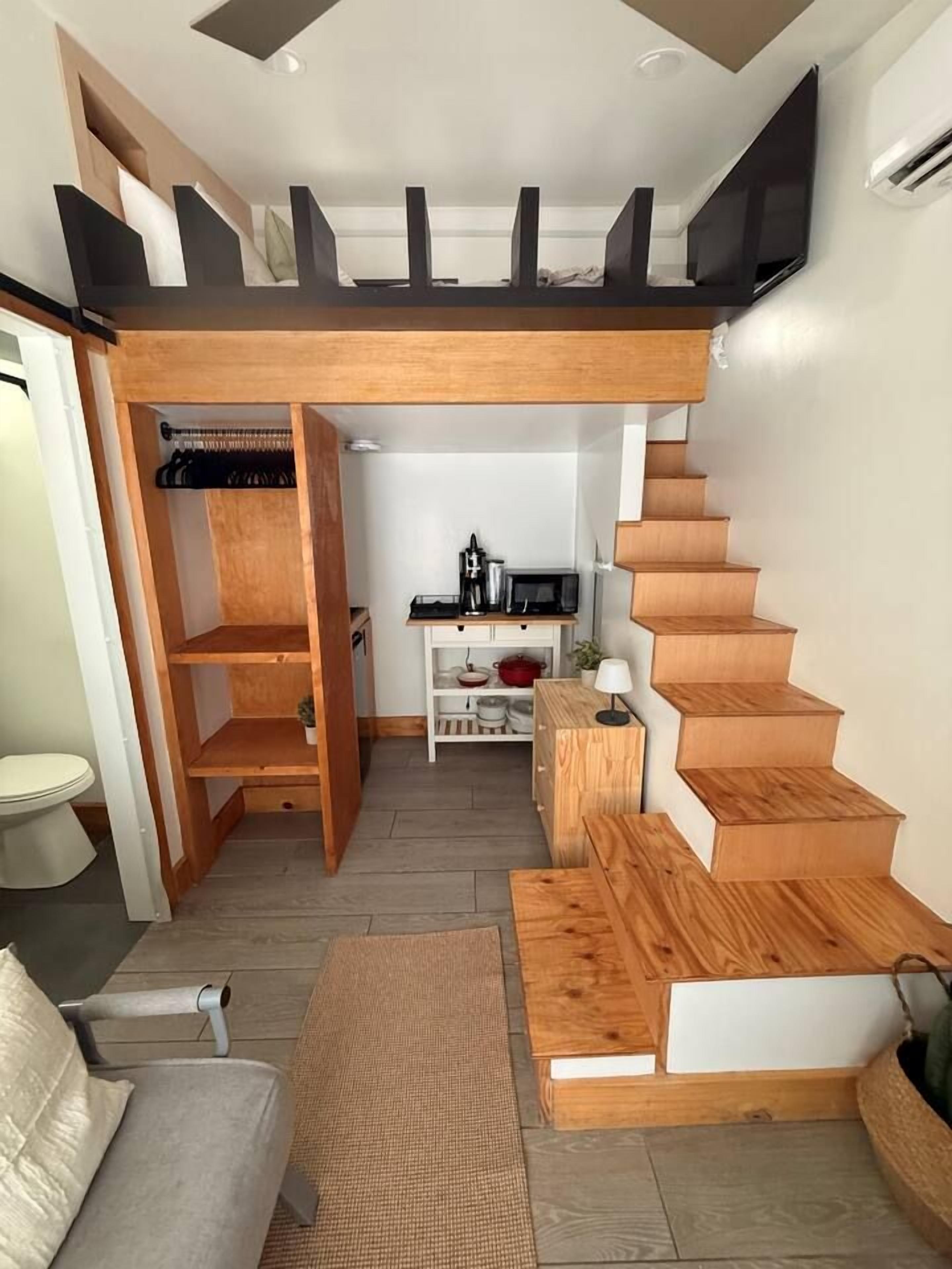 A modern interior with a wooden staircase, a sofa, and a kitchen area.