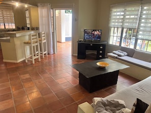 A living room with a sofa, a coffee table, a TV, and a kitchen area with a counter and chairs. - RESIDENCIAL LAUNDRY CNET (Las Terrenas)