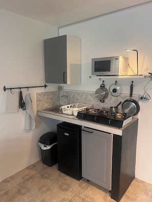 A compact kitchen with a microwave, stove, and small refrigerator. - RESIDENCIAL LAUNDRY CNET (Las Terrenas)