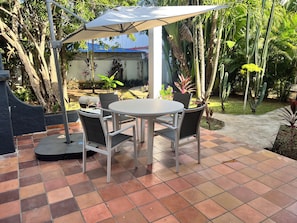 An outdoor patio with a round table and four chairs, surrounded by a variety of plants and trees. - RESIDENCIAL LAUNDRY CNET (Las Terrenas)