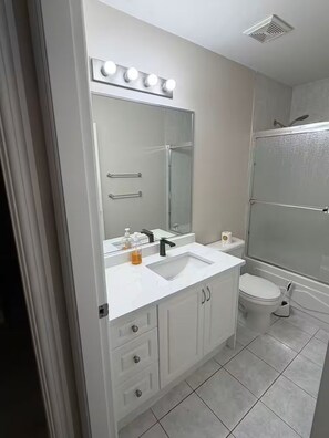 A bathroom with a white sink, mirror, and vanity, a toilet, and a glass-enclosed shower. - Brand new guest suite in Burnaby (Burnaby)