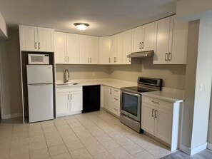 A kitchen with white cabinets, a microwave, a refrigerator, a dishwasher, a stove, and a sink. - Brand new guest suite in Burnaby (Burnaby)